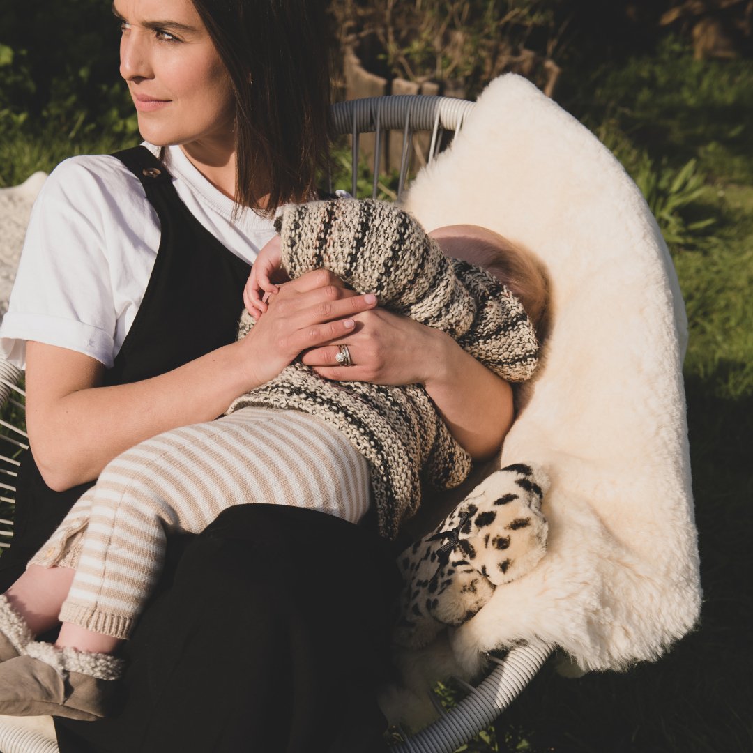 Baby asleep in mothers arms on sheepskin, help baby sleep