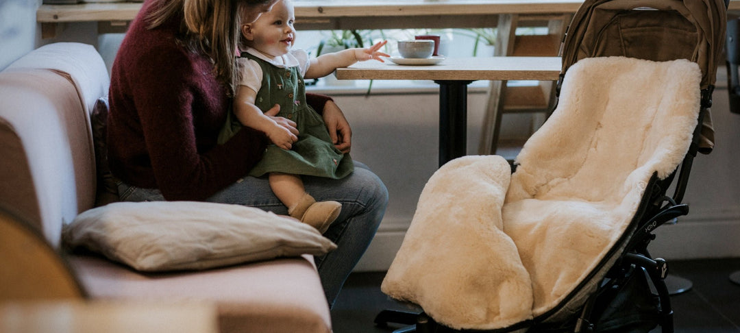 Footmuff in a pram admist a cosy coffee shop setting