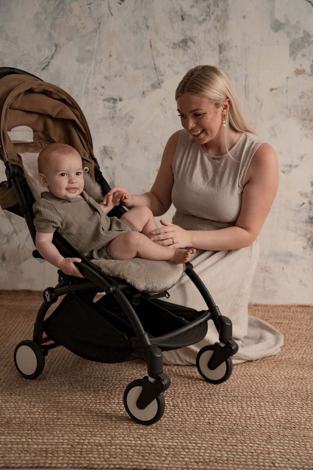 mother kneeling next to baby in a pram