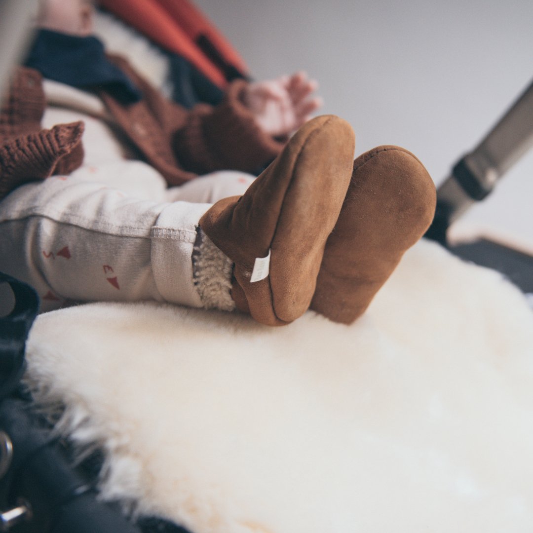 baby on sheepskin pram liner with lambskin baby booties