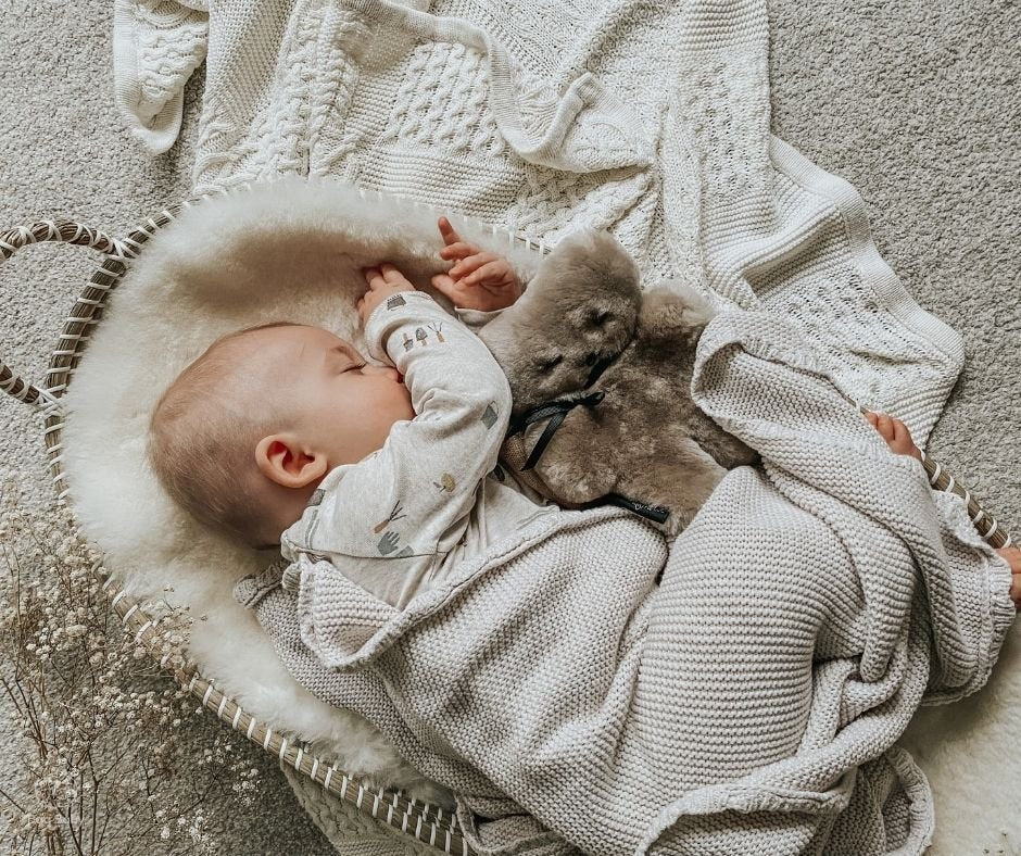 baby asleep in moses basket with sheepskin liner