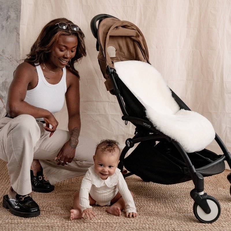 Sheepskin pram liner fitting perfectly in a  cybex pram with happy baby comfortable in the summer 