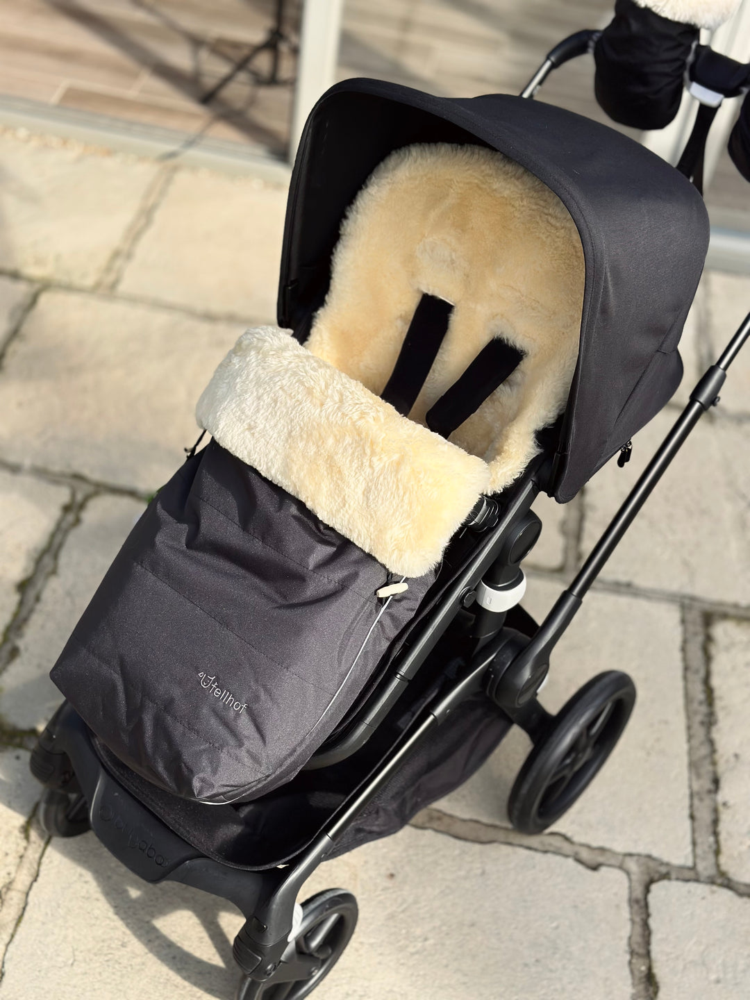 Sheepskin pram footmuff with honey lining and black waterproof outer made by Fellhof