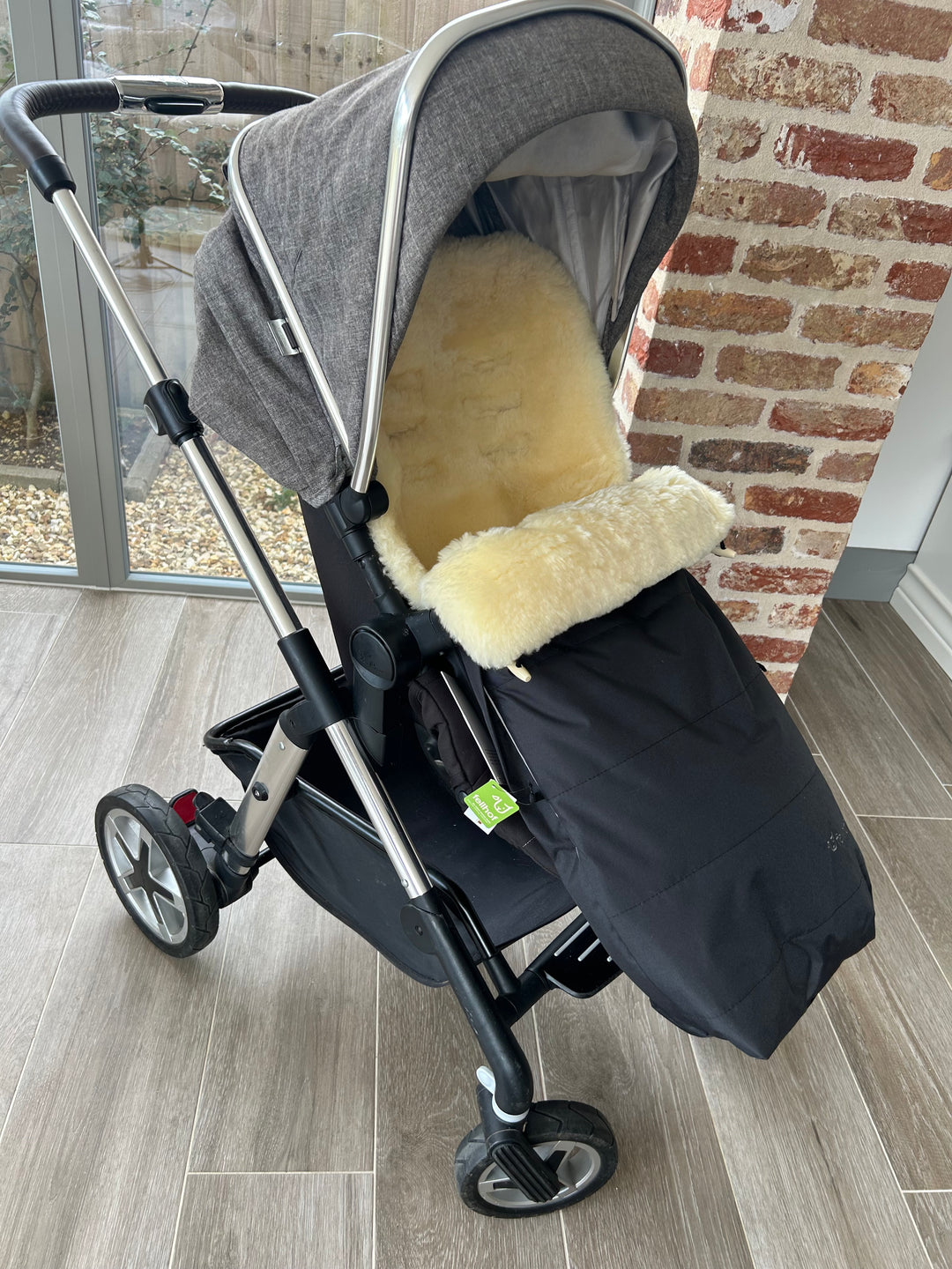 Fellhof Garmisch sheepskin pram footmuff shown in a silver cross pram to keep a baby warm and cosy in the winter months