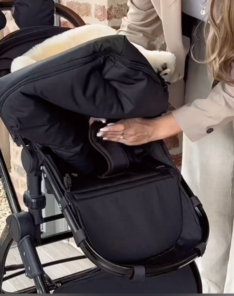 Sheepskin pram footmuff being fitted into a fixed harness cybex pram to prevent it slipping