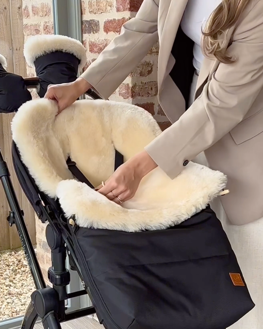 Harness straps being passed through a sheepskin footmuff to show the fitting in an ickle bubba pram