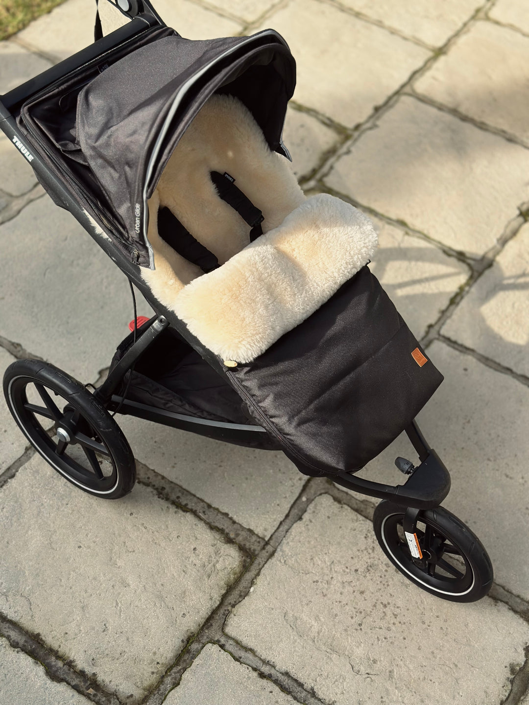 Baa Baby Sheepskin Pram footmuff in black waterproof cotton outer lined with milk merino to keep baby warm.  Footmuff is shown in the Urban glide pram