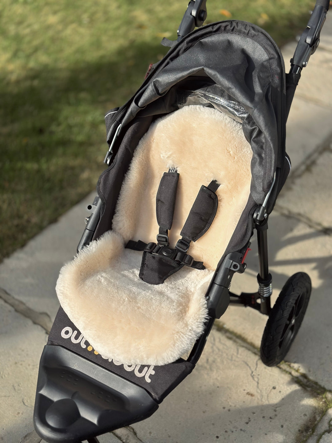 Sheepskin pram liner in milk fitting in an Out n About 3 wheeled pram