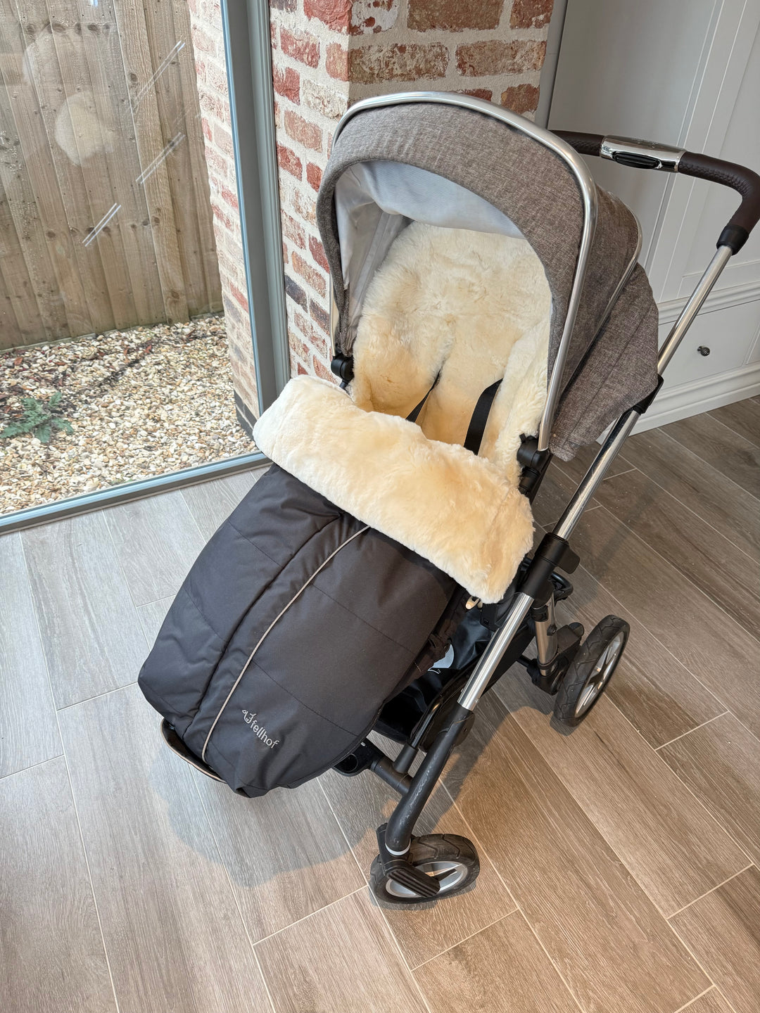 Fellhof sheepskin premium footmuff shown in a silver cross pram