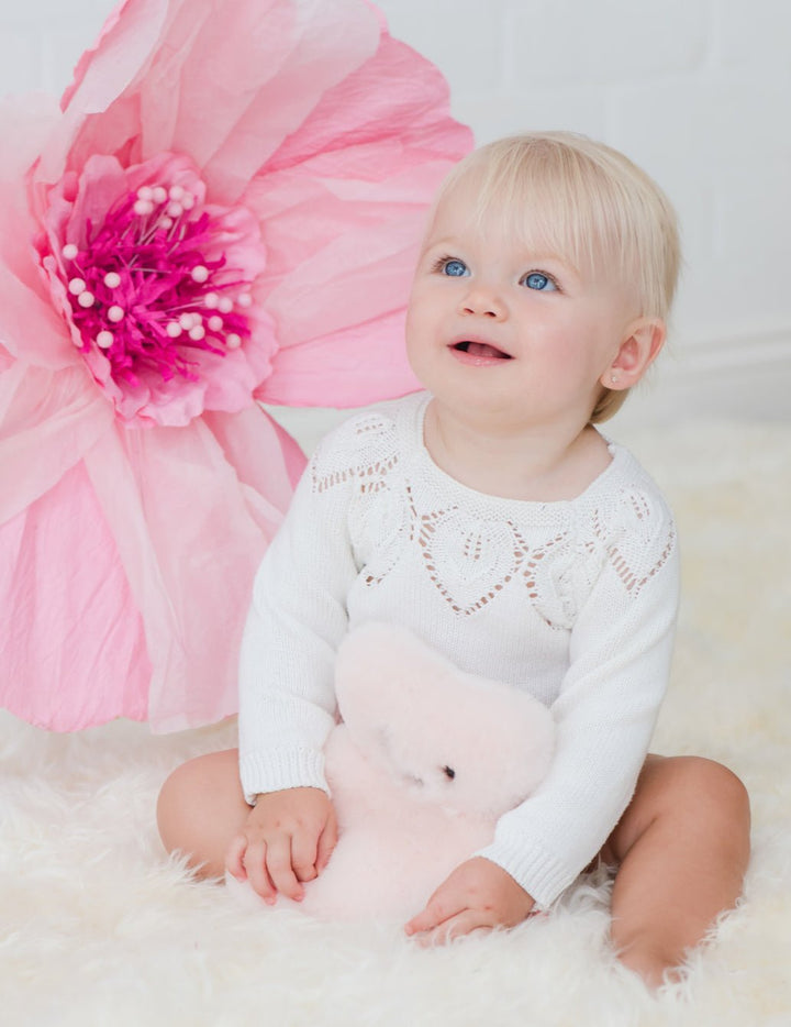 Baby girl toddler on a sheepskin rug cuddling rosie baby bear, FLAT sheepskin teddy