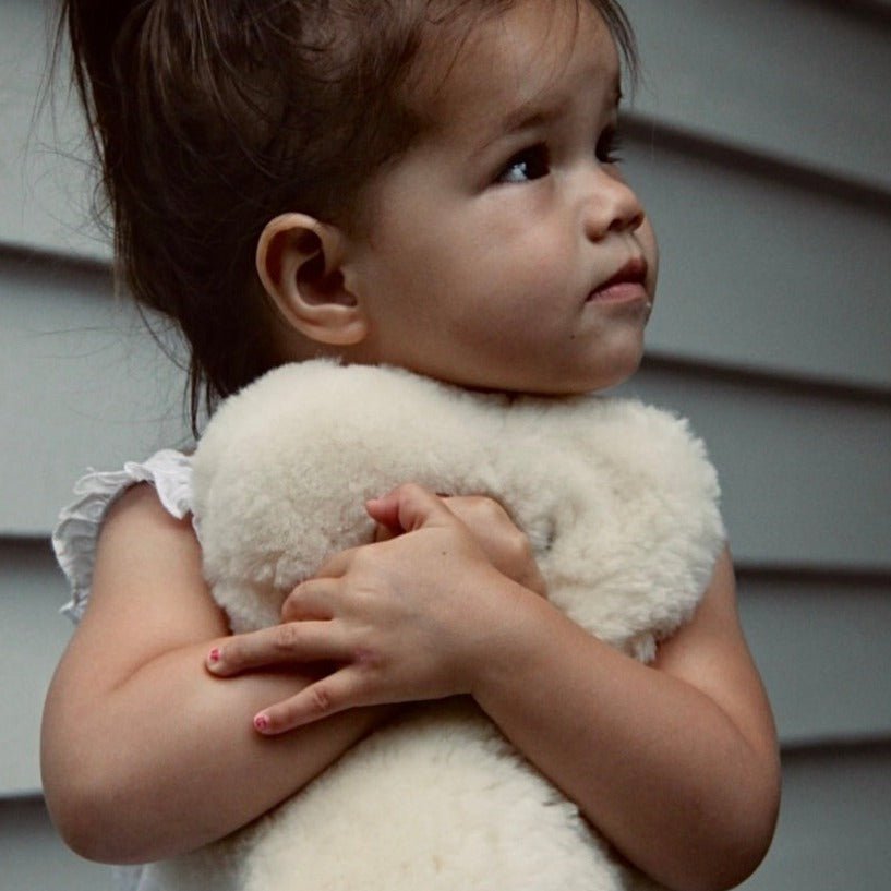 Girl Hugging Big FLATOUT Bear in Milk for Neutral Nursery Decor