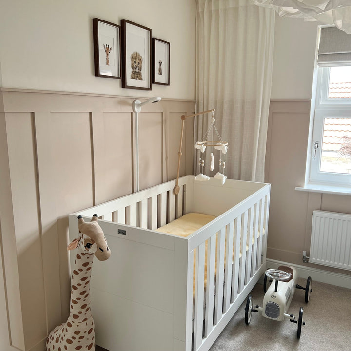 Mattress cover shown in a neutral nursery  with a pale honey natural sheepskin cot topper to help baby sleep