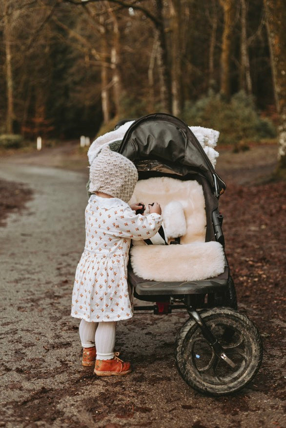 Neutral milk sheepskin buggy liner in a 3 wheeled running pram