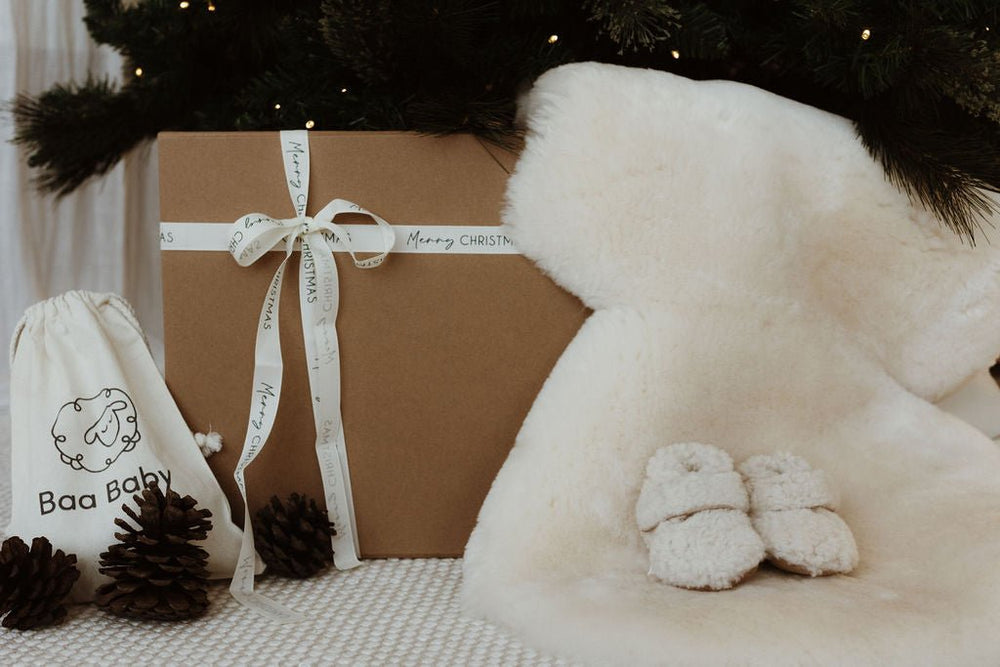 Newborn baby gift box with sheepskin pram liner and merino boucle teddy booties with Christmas ribbon and gift note