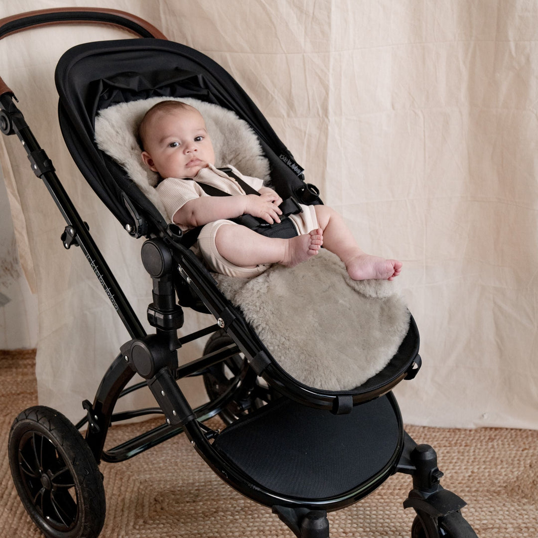 Pale Brown Natural Shorn Lambskin Bugaboo™ Pram Liner for Comfort and Sleep, baby laid in a pram lined with neutral sheepskin