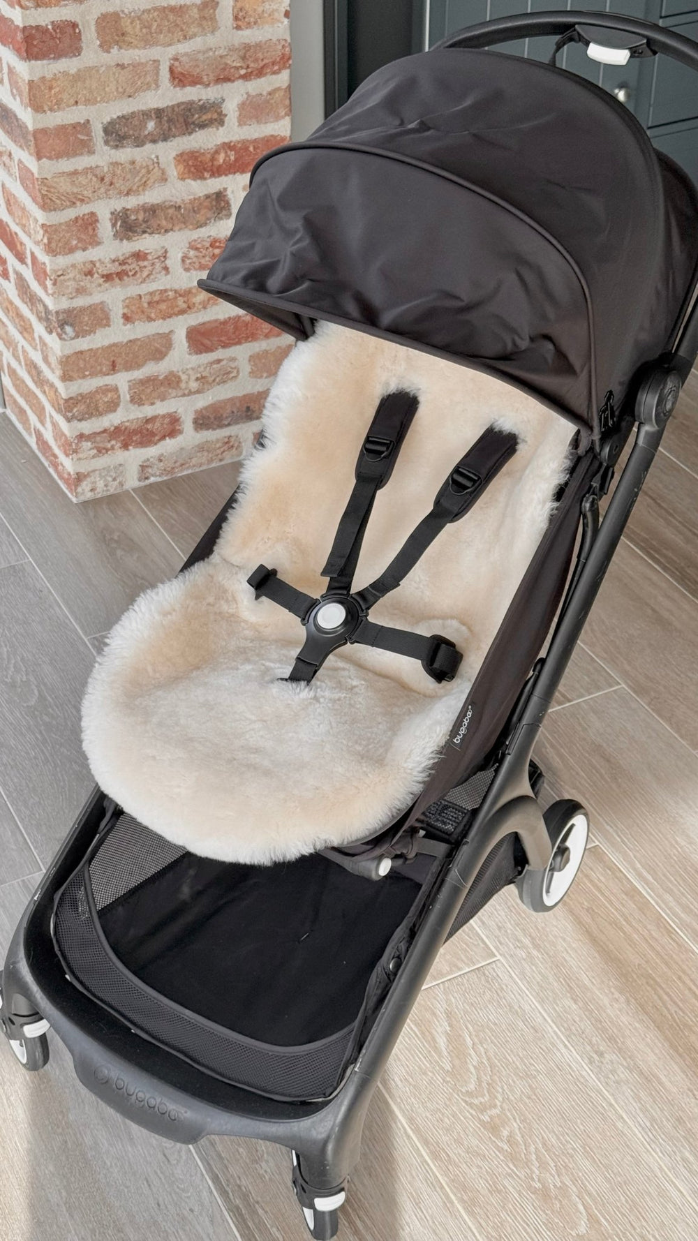 Black Bugaboo Butterfly travel pram show unfolded with a neutral milk sheepskin pram liner for added comfort and temperature regulation